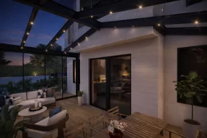 Image Mar 16 2026 12_14_25 PM copy Nighttime modern outdoor living area with glass walls, string lights, and a wooden deck seating area (sofa, coffee table with candles).