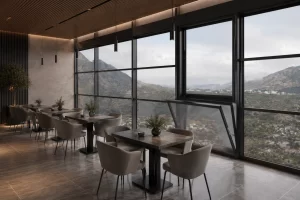 giyotincam Modern restaurant with gray chairs and marble tables by floor-to-ceiling windows overlooking a mountainous landscape outside.